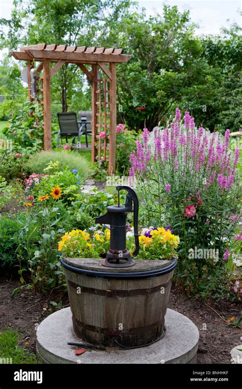 An Old Decorative Water Pump In The Garden With Flowers In Reinland