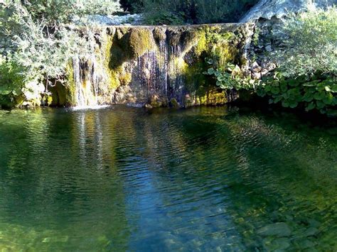 There Is A Small Waterfall In The Middle Of This Lake With Green Algae