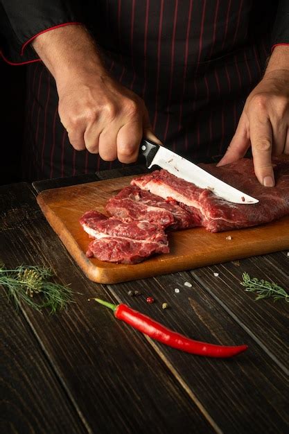 Premium Photo The Chef Cuts Raw Fresh Beef Meat On A Cutting Board