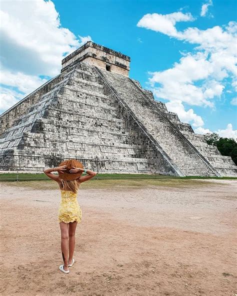 A Woman In A Yellow Dress And Straw Hat Standing In Front Of An Ancient