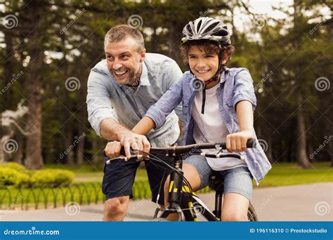 Niño Aprendiendo A Andar En Bicicleta Con Su Feliz Papá Foto De Archivo