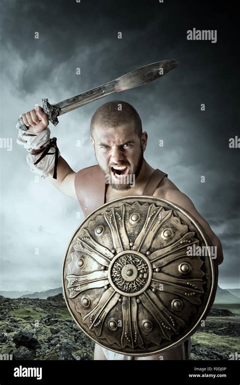 Gladiator or warrior posing with shield and sword outdoors ready for ...