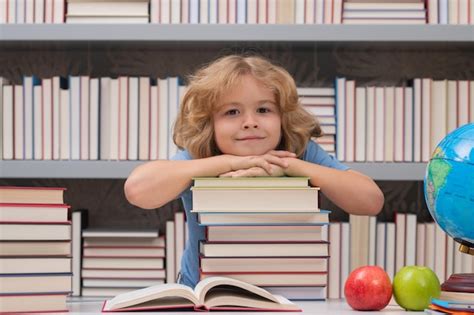 Школьник со стопкой книг в библиотеке портрет симпатичного школьника и ...