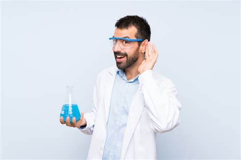 Joven científico sosteniendo frasco de laboratorio escuchando algo