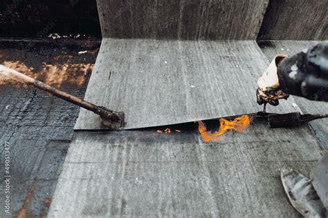 Construction Workers Roofers Installing Rolls Of Bituminous