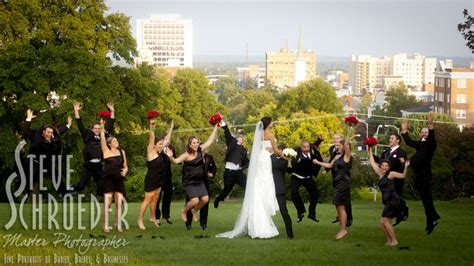 A Bride And Groom Surrounded By Their Wedding Party In The Park With