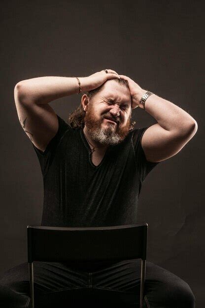 Premium Photo Bearded Man Sitting On Chair Against Black Background