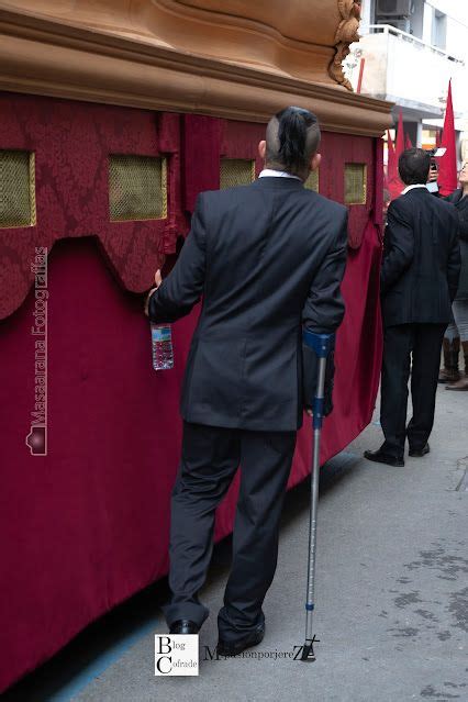 A Man In A Suit And Crutches Is Standing Next To A Red Train