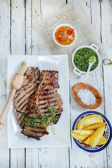 Churrasco Steak With Side Dishes criolla Sauce, Chimichurri Sauce And Potato Wedges Photograph ...