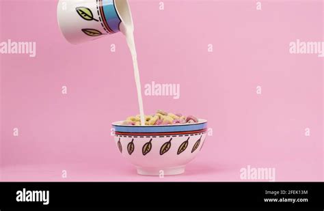 Pouring Milk From Pitcher Into Bowl Of O Shaped Cereal With Pink