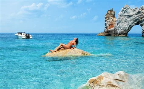 La Belle Fille Dans Le Bikini Prend Un Bain Du Soleil Sur Une Roche