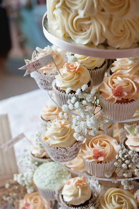 Three Tiered Cupcake Display With White And Pink Frosting Flowers On Each Tier