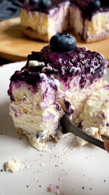 A Piece Of Blueberry Cheesecake On A White Plate With A Fork In It