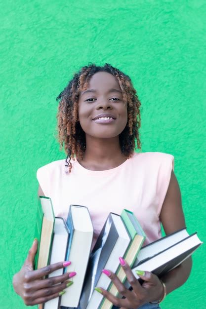 Una Mujer Afroamericana Sonriente Sostiene Una Pila De Libros Sobre Un