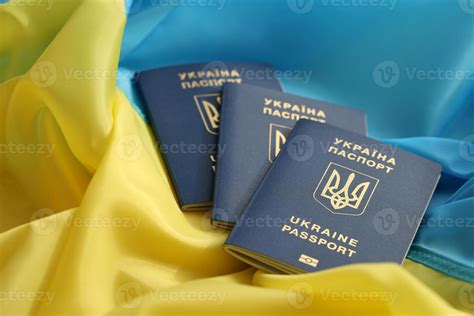 Three Ukrainian Biometrical Passports On Folded Waving Flag Of Ukraine