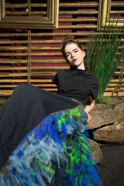 A Woman Sitting On Top Of A Rock Next To A Plant