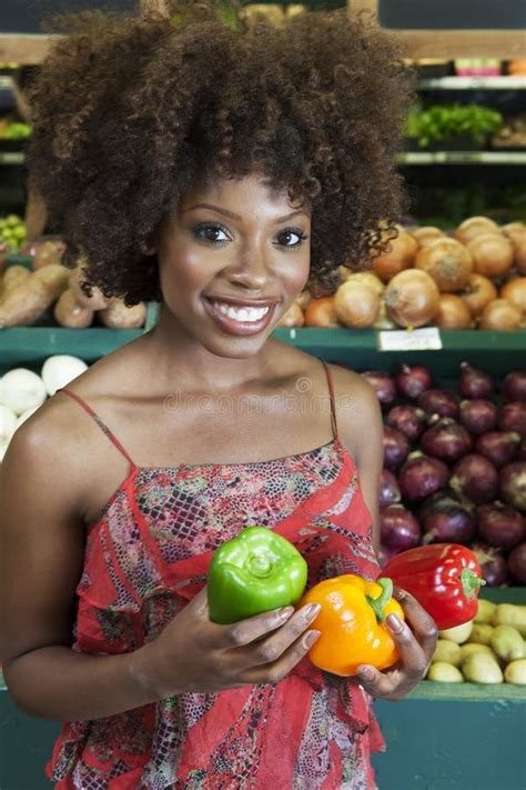 African American Woman Holding Bell Peppers At Supermarket Stock Image