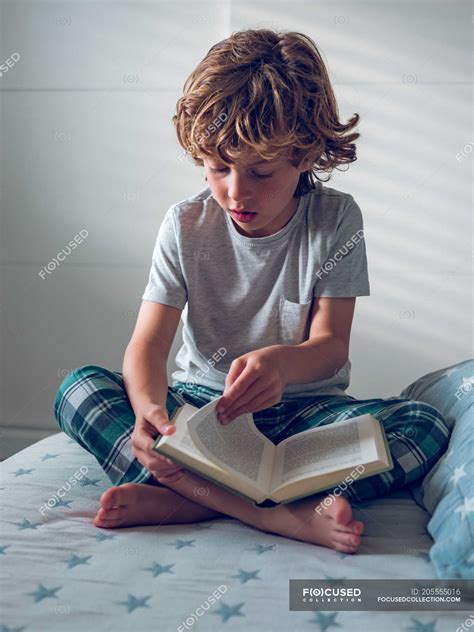 boy reading book  bed crossed legs fairytale stock photo