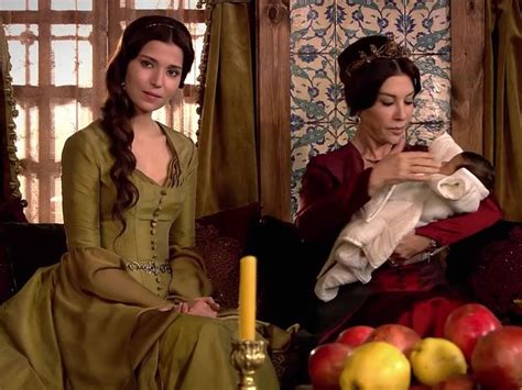 Two Women Dressed In Period Clothing Sitting On Couches With Apples And