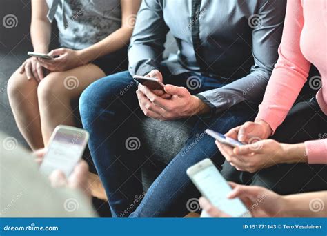 Group Of Millennial Business People Using Mobile Phones And Sitting On