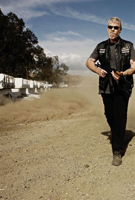 a man in black jacket and sunglasses walking on dirt road