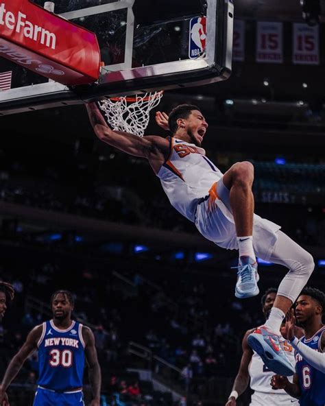 a basketball player dunking the ball in front of his team mates during ...