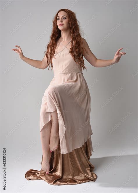Full Length Portrait Of Beautiful Female Model With Long Brunette Hair Wearing A Creamy Pink