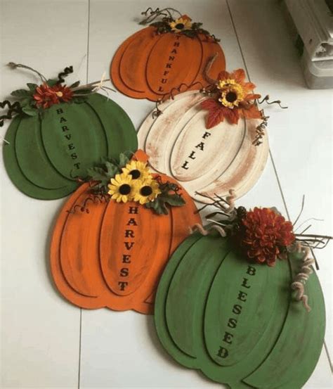 Four Pumpkins With The Words Happy Harvest Painted On Them And Flowers