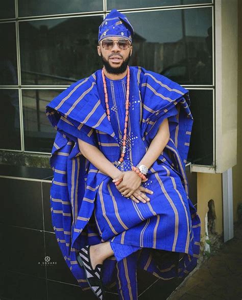 A Man In A Blue And Gold Outfit Sitting On The Ground Next To A Building