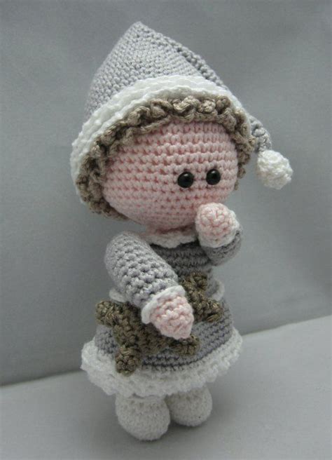 A Small Crocheted Doll Wearing A Hat And Dress