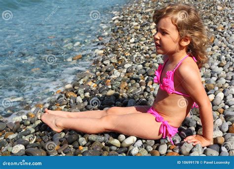 A Menina Senta Se Na Praia Foto De Stock Imagem De Litoral