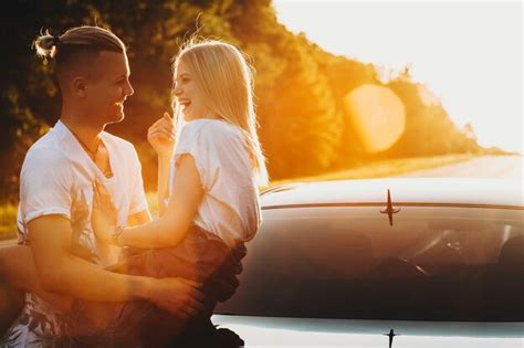 Premium Photo Side View Of Cheerful Couple Embracing And Leaning On Car Trunk At Roadside In