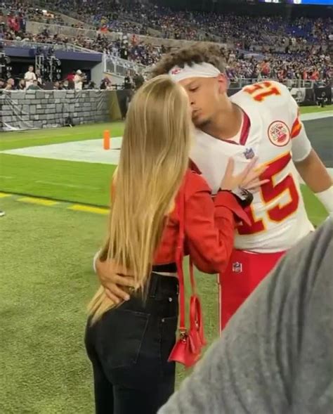 a man kissing a woman on the sidelines at a football game