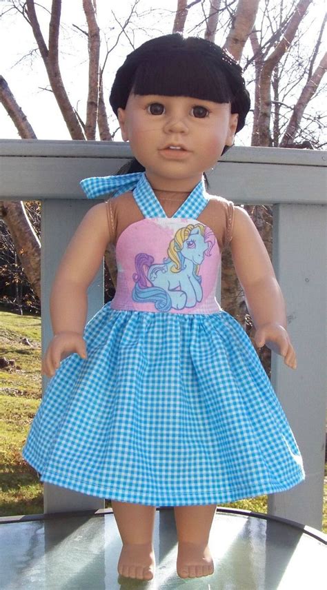 The Doll Is Wearing A Blue And White Dress With A Pink Pony On Its Chest