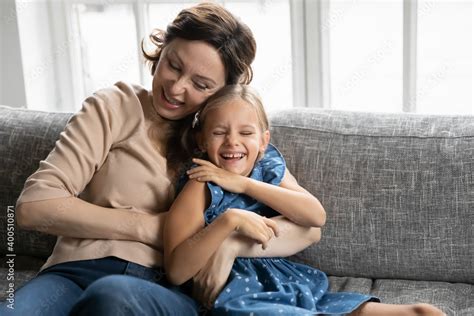 Happy Mature Grandmother And Granddaughter Having Fun Tickling On Couch At Home Close Up