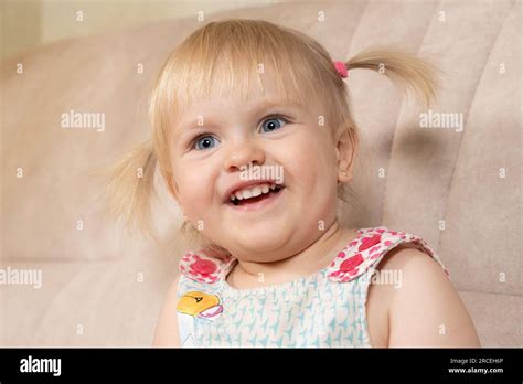 Portrait Of A Year Old Blonde Girl With Blue Eyes With Two Ponytails Looking To The Side Stock