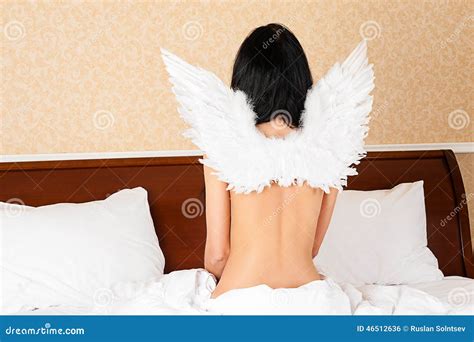 Der Brunette Der Auf Dem Bett Mit Engel Sitzt Beflügelt Stockfoto Bild von brünette engel