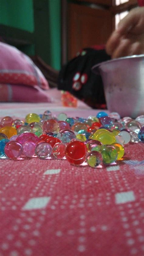 a bowl full of glass beads sitting on top of a pink tablecloth covered bed