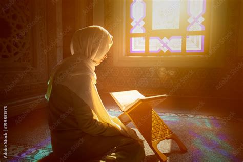 Young Muslim Woman Reading Quran In The Mosque And Sunlight Falling