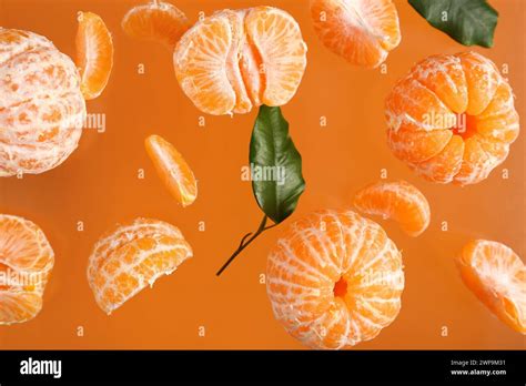 Flying Sweet Peeled Mandarins And Leaves On Orange Background Stock