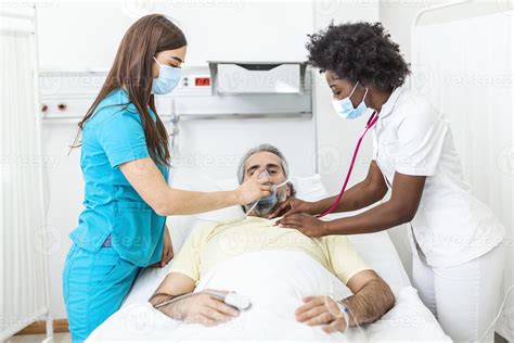 Nurse Puts Oxygen Mask On Elderly Man Patient Lying In The Hospital