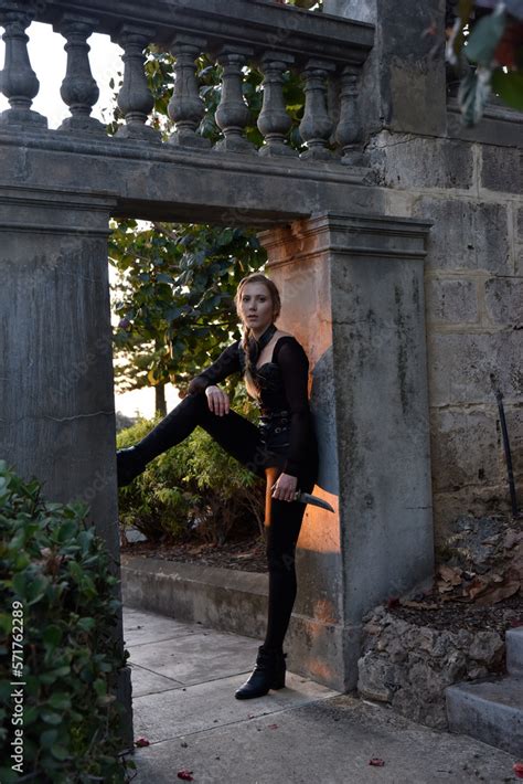 Full Length Portrait Of Beautiful Female Model With Blonde Plait Wearing Black Leather Catsuit