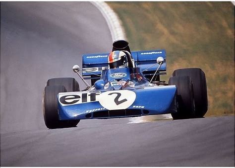 A Man Driving A Blue Race Car Down A Road