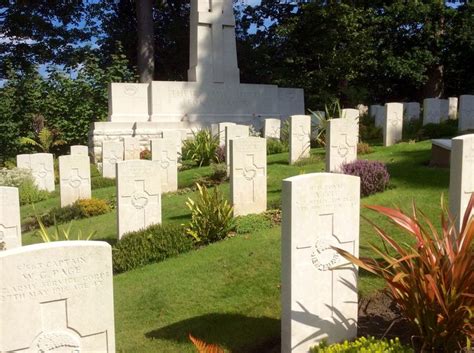 Many Headstones Are In The Grass Near Some Trees And Bushes With Plants