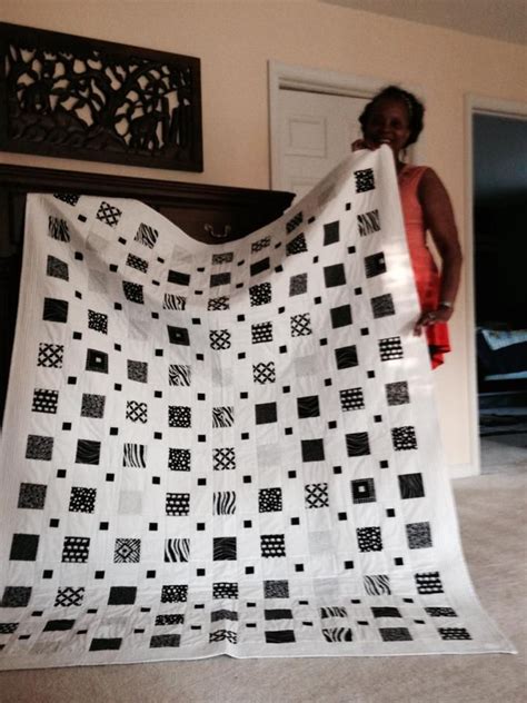 A Woman Standing Next To A White And Black Quilt