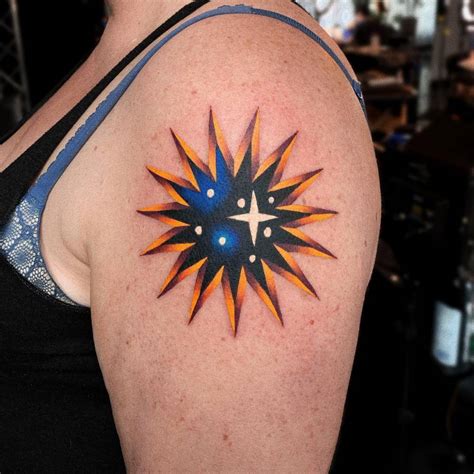 Sun/star tattoo located on the upper arm.