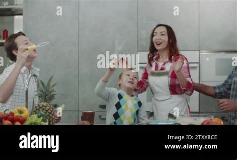 Mature Parents Playing With Their Two Sons In A Modern Kitchen Making Bubbles Stock Video