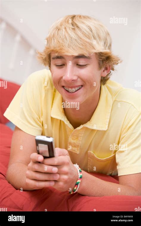 Teenage Boy Lying On Bed Using Mobile Phone Stock Photo Alamy