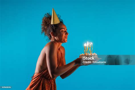 Young Woman Blowing Out Candles On A Birthday Cake That She Is Holding