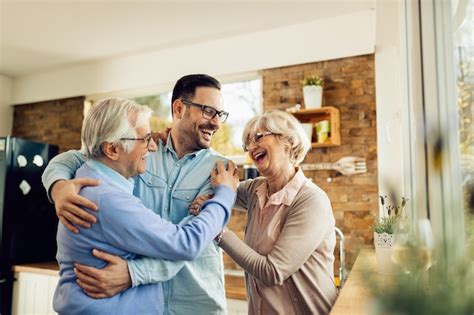 Free Photo Happy Mature Parents Having Fun While Embracing Their Adult Son Who Came To Visit